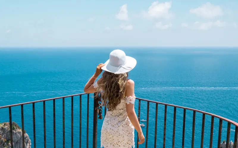 Woman in white dress and hat enjoying sea view