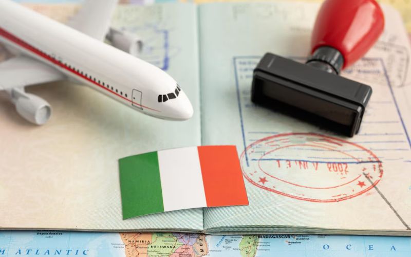 Italy visa concept with miniature airplane, passport stamps, Italy flag, and rubber stamp