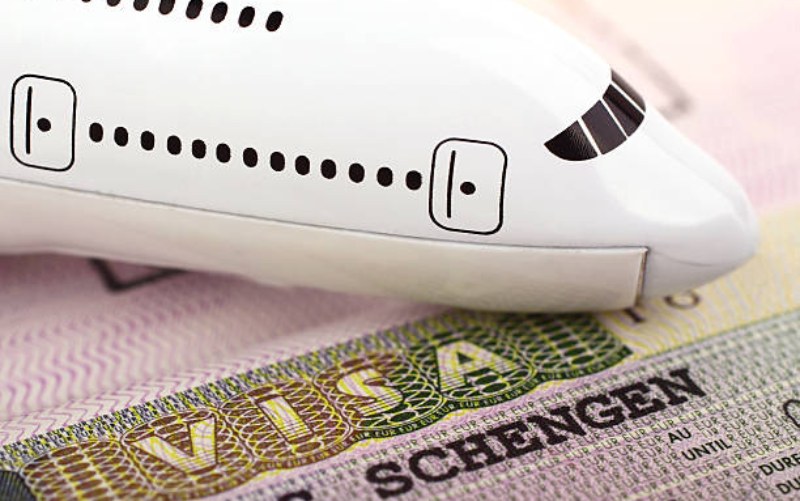 Model airplane on top of visa document, symbolizing travel and visa requirements.